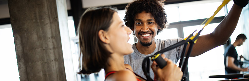 Woman exercising with man at gym