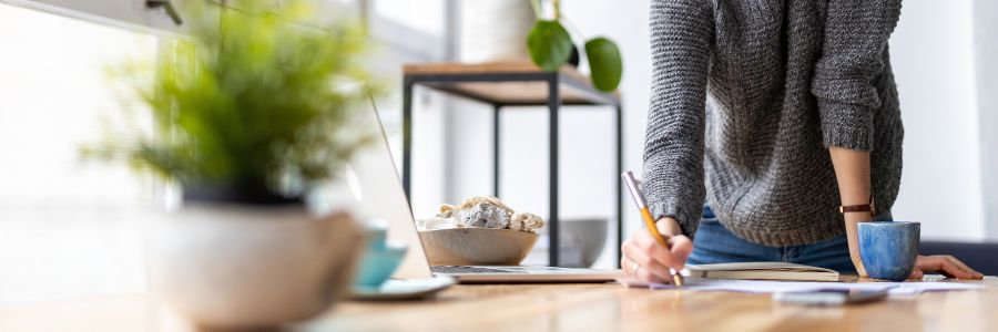 Person standing at table writing something down