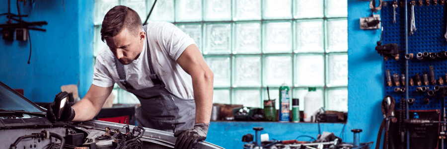 young man fixing up cars in a garage exploring the possibility of starting his own business.