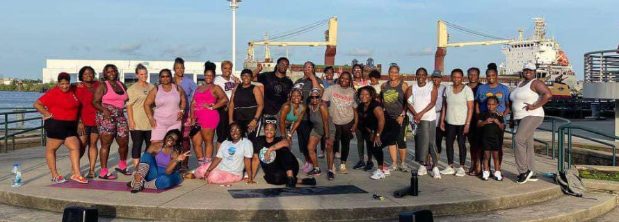 Group of women that attended Dee's fitness class posing on a waterfront.